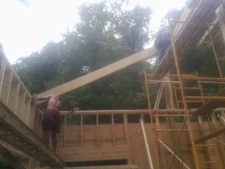 Carpenter raising a rafter beam on a new second story frame in Blairsville