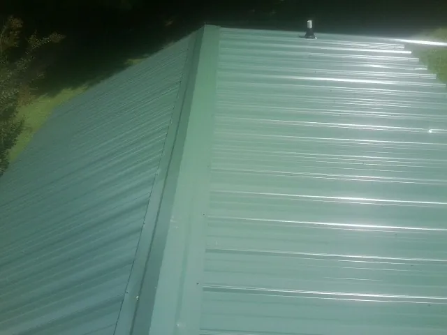 New green metal panels meeting at the ridge of a roof — Flat Roof Repair work by our crew in Blairsville