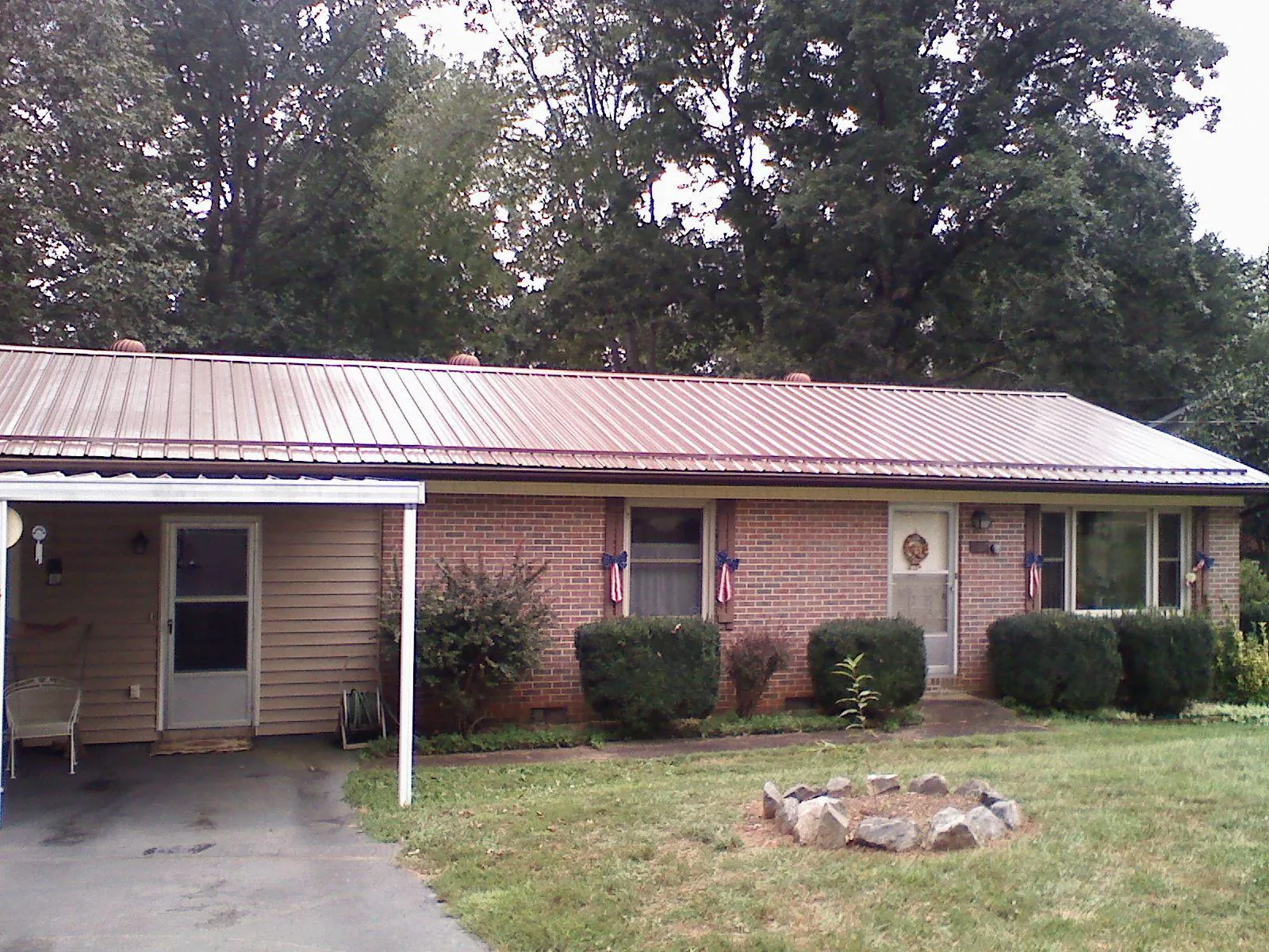 Bronze metal roof and carport on a brick ranch home — Roof Repair work by our crew in Blairsville