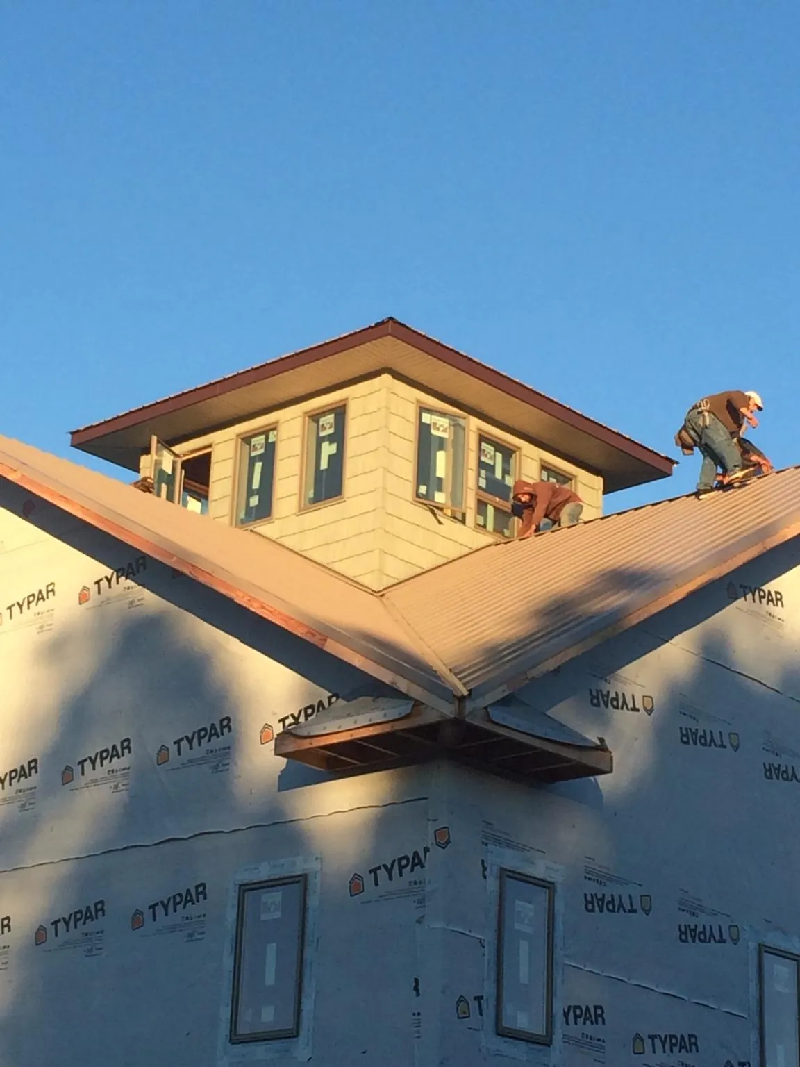 Roofers working around a rooftop cupola on a new metal roof at sunset — Roof Waterproofing in Blairsville by Roofing Brothers